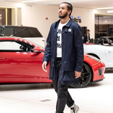 Cheshire Fashion Week Man walking indoors near red sports car.