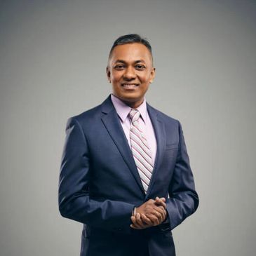 Professional man in a navy suit and striped tie smiles confidently.