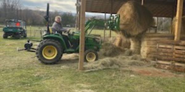 Lady on tractor lifting round bale