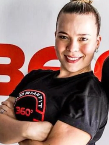 Woman in black shirt and red leggings smiling, standing with crossed arms.
