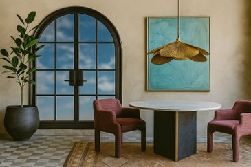 Hospitality design with round table, burgundy chairs, and a large arched window.
