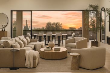 Modern living room with beige furniture and sunset view.