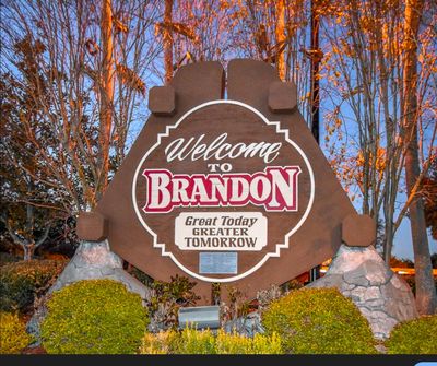 A wooden sign welcoming visitors to Brandon with a scenic background.