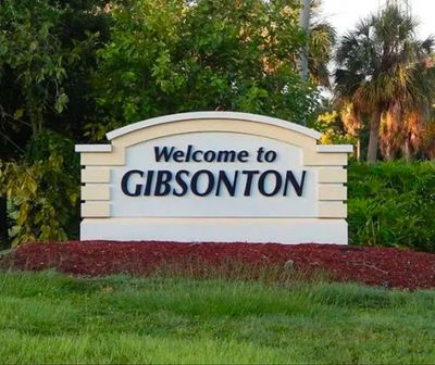 Welcome sign for Gibsonton surrounded by greenery.