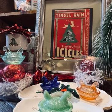 Vintage holiday glass bird decorations on plates with framed Christmas sign.