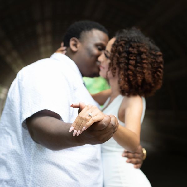 Couple holding hands and sharing a kiss in a tunnel.