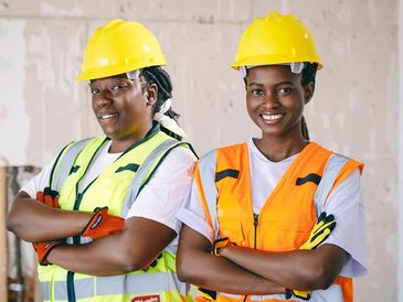 Two female construction workers wearing hard hats and safety vests.