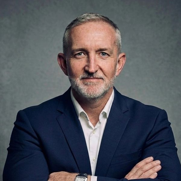 Confident middle-aged man in a suit with arms crossed.