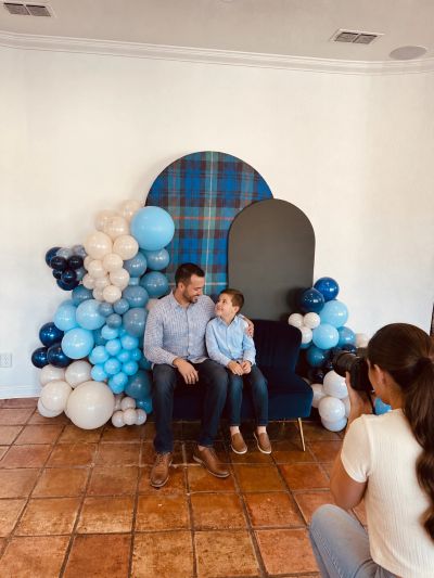 father and son posing for a picture Infront of custom blue balloon birthday party installation at ev