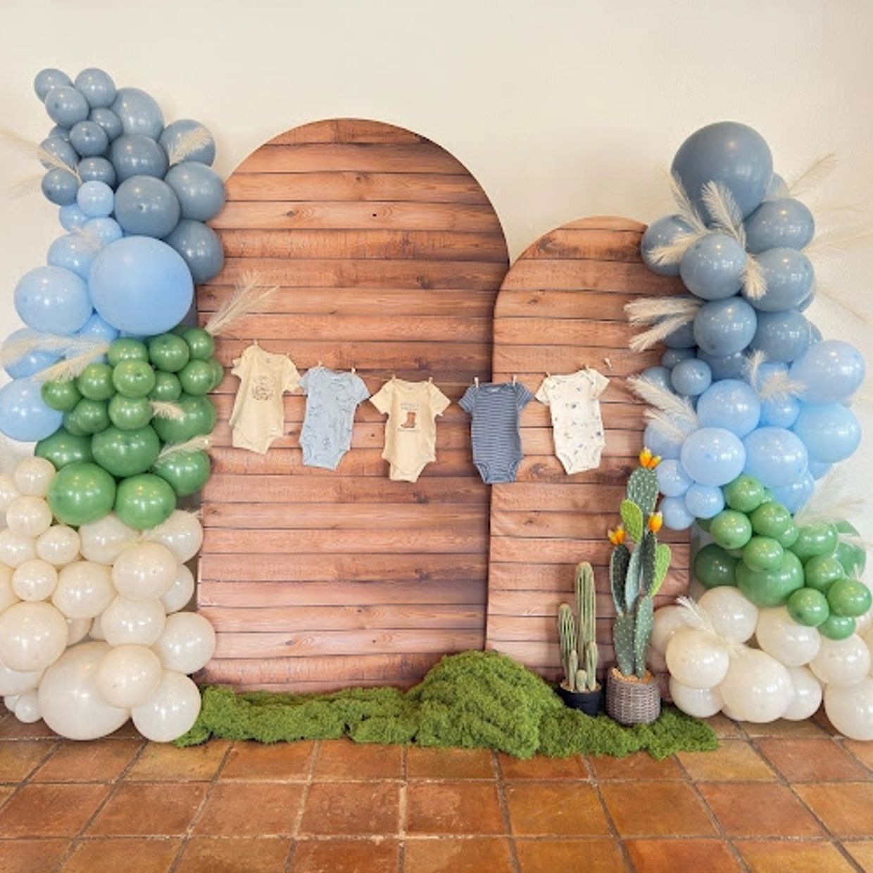 photo backdrop for baby shower gender reveal with blue green and cream balloons and greenery
