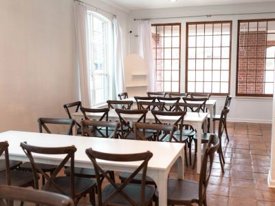 Bright room with white tables and wooden chairs.