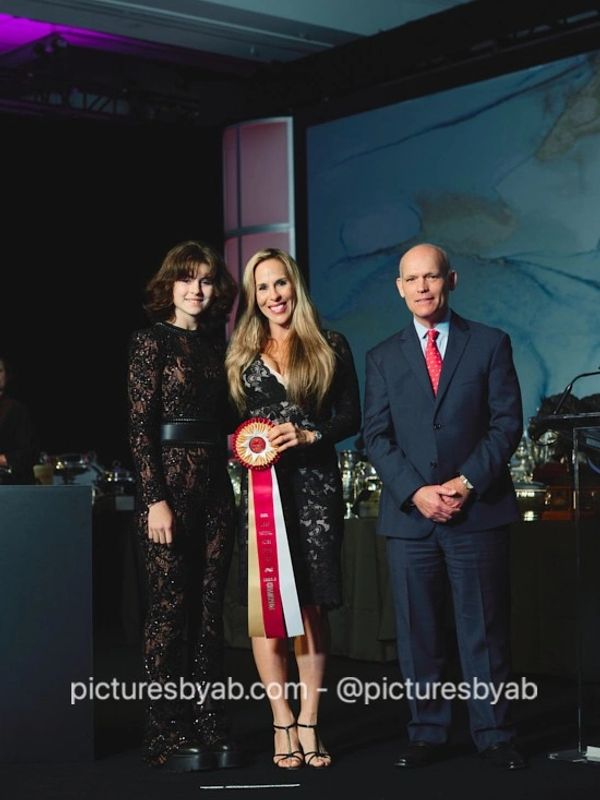 Three people pose on stage at an awards ceremony.