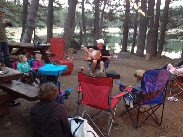 Group camping with guitar music in the woods.
