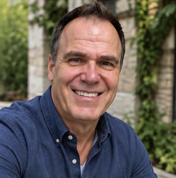 Smiling middle-aged man in a blue shirt outdoors.
