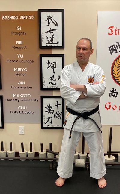 instructor posing in front of framed Japanese character