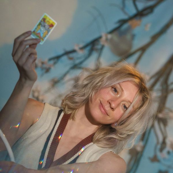 Woman holding tarot card with a serene expression.