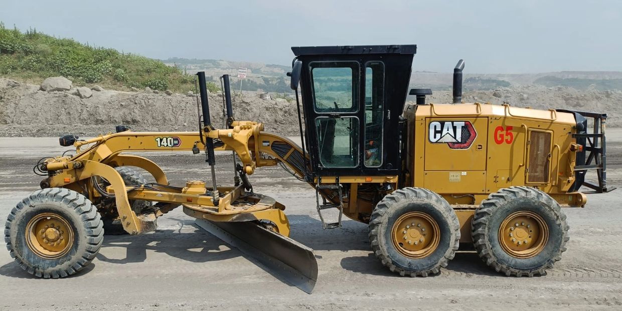 Yellow CAT 140 GC motor grader on a construction site.