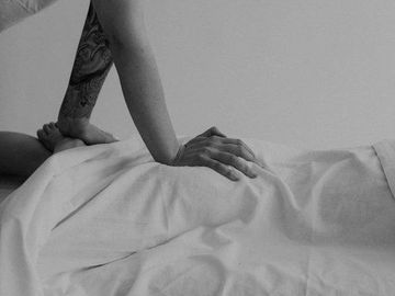 A person receiving a massage with visible arm tattoo in black and white.