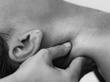 Person receiving a neck massage with fingers pressing muscles.