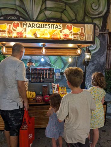 Family ordering at a Marquesitas food stand at night outdoors.
