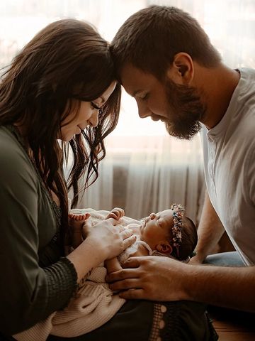 mom and dad holding newborn baby in photography studio