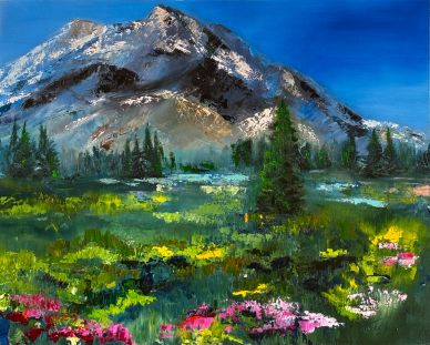 Colorful meadow with wildflowers beneath a towering mountain under a clear blue sky.