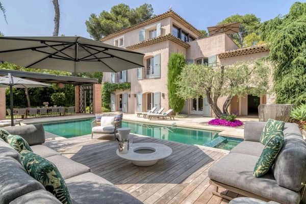 Luxurious outdoor patio with pool and comfortable seating under umbrellas.