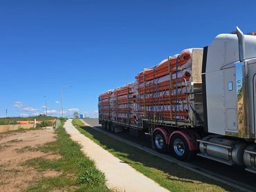Prime mover hauling stacked PVC pipes on flat top trailer for Australian freight