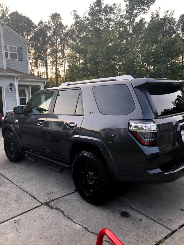 Dark gray SUV parked on a driveway near a house with trees in the background.