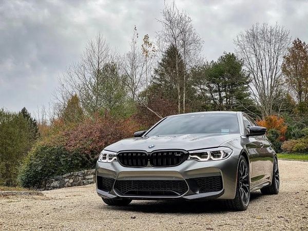 Sleek silver BMW parked on a gravel path with autumn trees in the background.