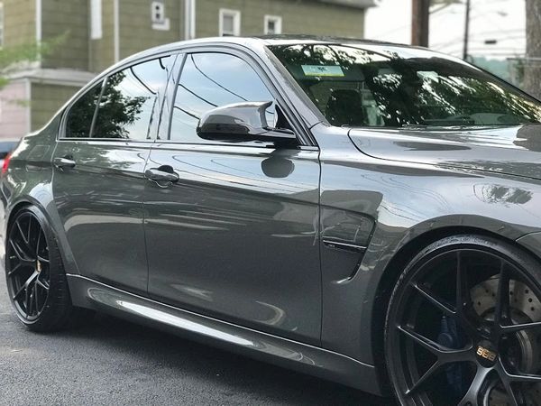 Sleek gray sports sedan with black BBS wheels parked on a residential street.