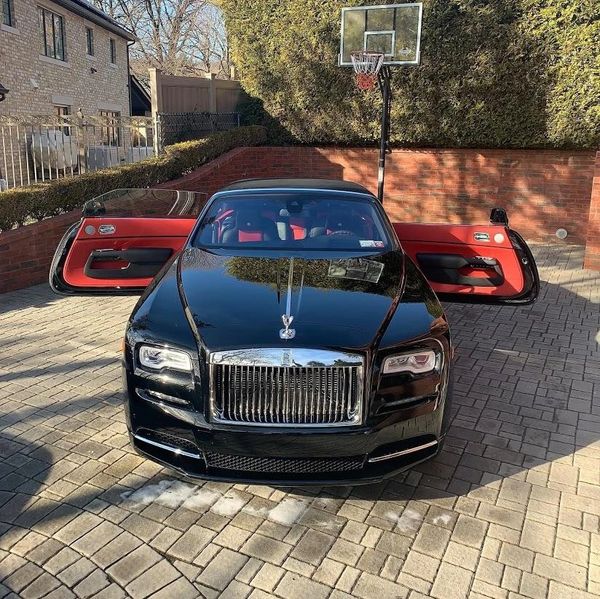 Black Rolls-Royce with red interior and open doors in a driveway.