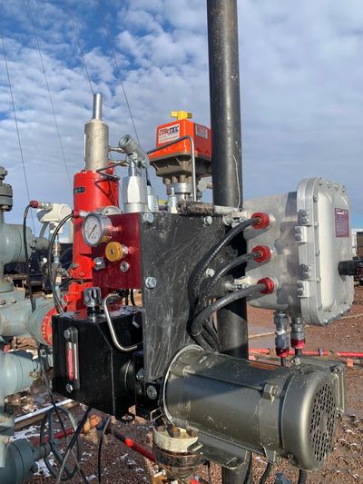 Industrial machinery setup with gauges and wires against a cloudy sky.