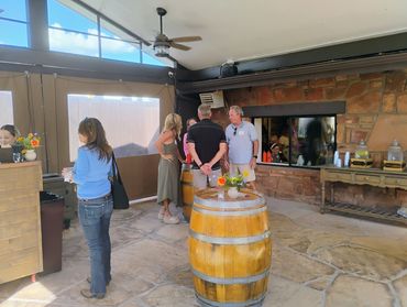 Outside tent area where people order drinks and gather around barrels to chat.