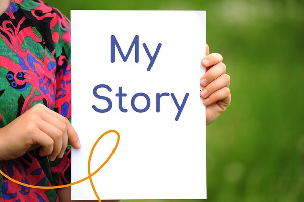 Image of a person holding a piece of paper with the words my story written on it