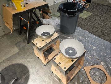 Two satellite dishes on wooden stands in a workspace.