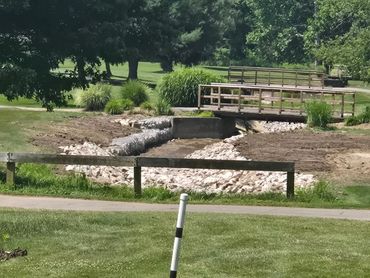 A small wooden bridge over a rocky canal in a park.