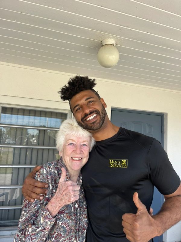 A young man and elderly woman smiling and giving thumbs up together.