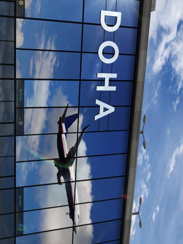 Reflection of an airplane and sunlight on the glass facade of Doha airport.
