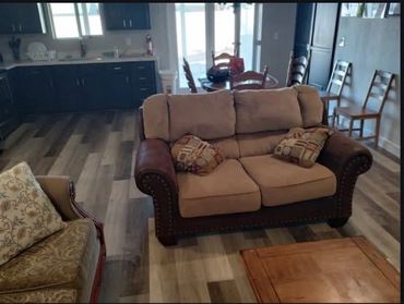 Cozy living room with cushioned sofa and wooden chairs.