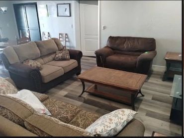 Cozy living room with three sofas and a wooden coffee table on laminate flooring.