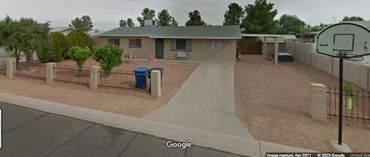 Single-story house with gravel yard and basketball hoop.