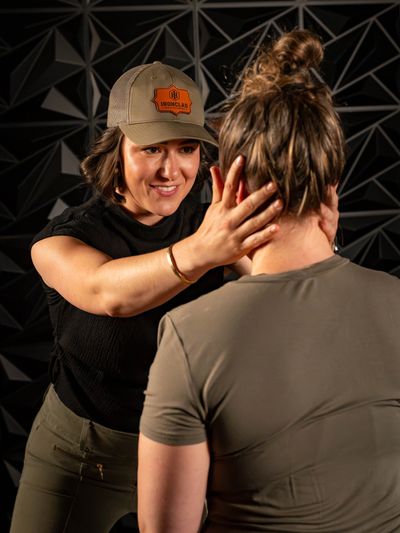 Woman gently touching another woman's head indoors.
