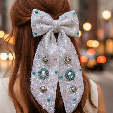 Woman with long hair adorned by a large, sequined bow in an urban setting.
