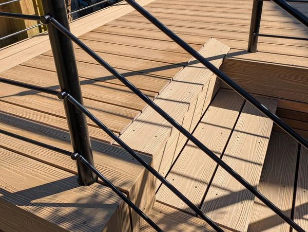 Large deck installation with metal handrail and stairs down to the lower garden level.
