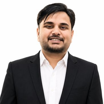 Man in black suit smiling against white background.