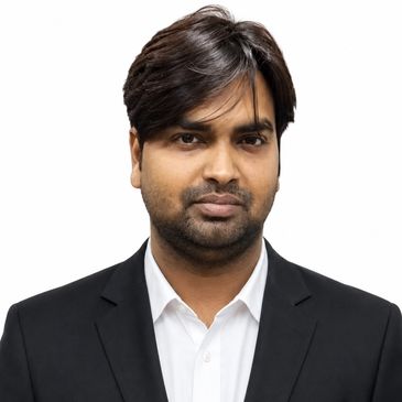 Man in a black suit and white shirt posing for a photo.