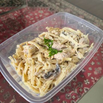 Creamy chicken pasta with mushrooms in a plastic container.