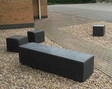 Outdoor seating with black rectangular and square benches on gravel near a brick building. bancas de acero inoxidable
papeleras
paradas