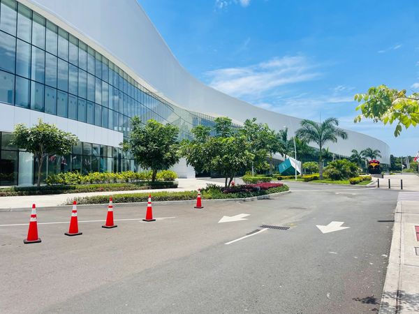 Modern building with glass facade and orange traffic cones on a sunny day.